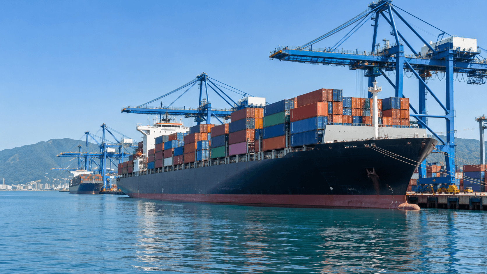 Container ship alongside cargo cranes in a busy international port